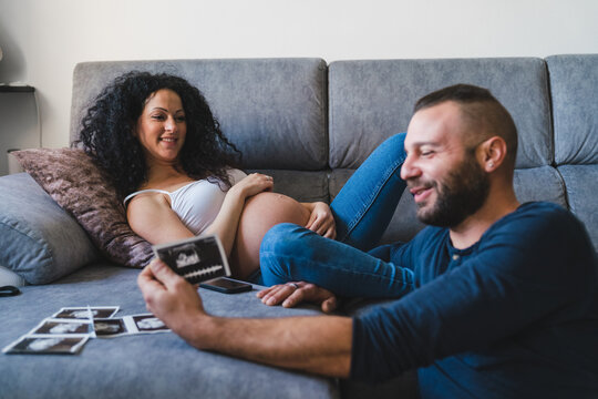 Happy Couple Expecting a Baby Relaxing on a Sofa