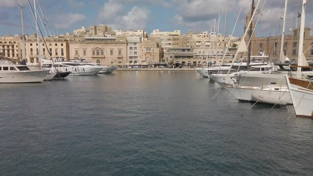 Sailing past Vittoriosa waterfront with boats moored in the waterway