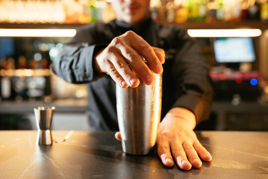 Bartender preparing cocktail in shaker at counter