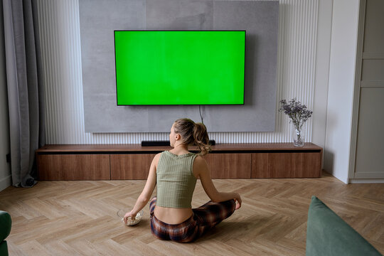 a woman is watching a movie on a green screen and eating popcorn