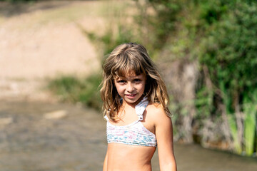 Smiling girl in swimwear near river