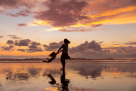 Mother swings child and plays on Beach in Costa Rica