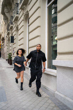 Young Couple Running On The Street.