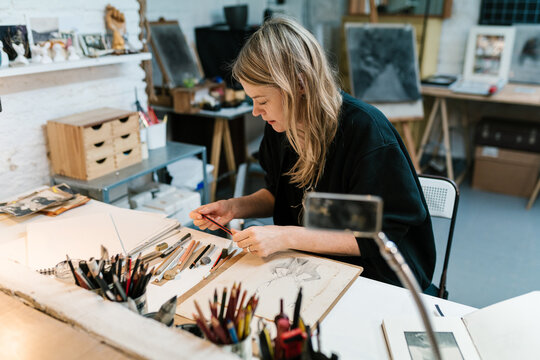 Blond artist selecting pencil during work