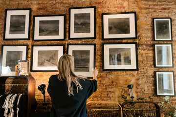 Painter hanging charcoal paintings on wall