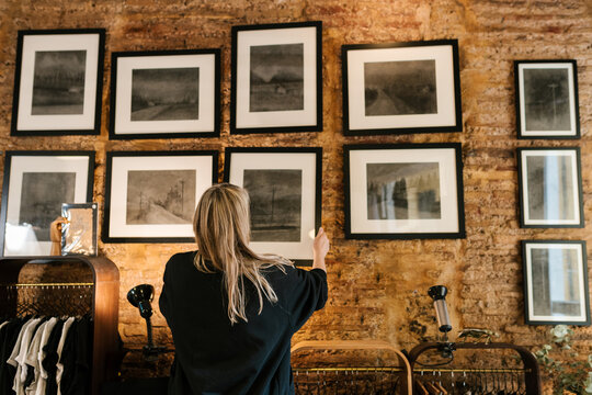Painter hanging charcoal paintings on wall