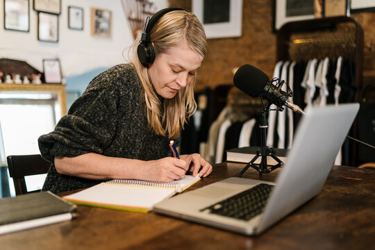 Podcaster in headphones taking notes in notebook