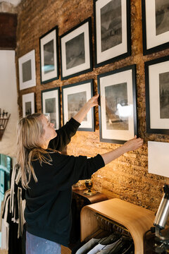 Creative artist hanging paintings on wall