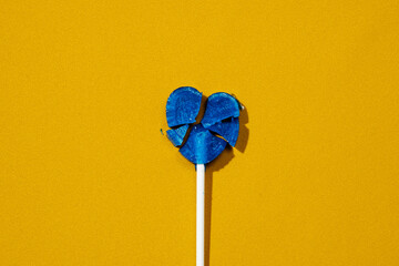 broken heart-shaped lollipop on fabric, as the Ukrainian flag