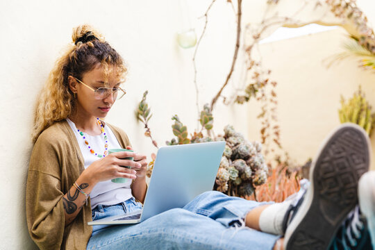 Woman holding a cup of coffee at pc