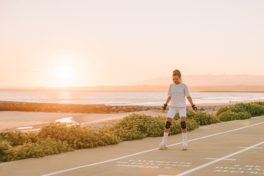 Young woman roller skating in sunset