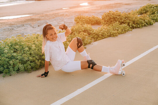 Female roller skater sitting on the road