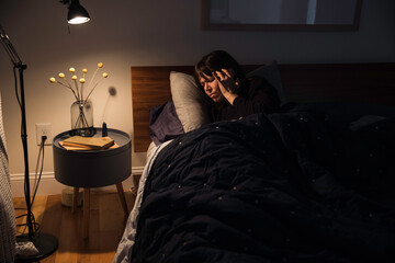 Woman laying in bed with a headache 