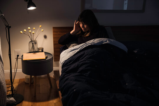 Woman laying in bed with a headache 