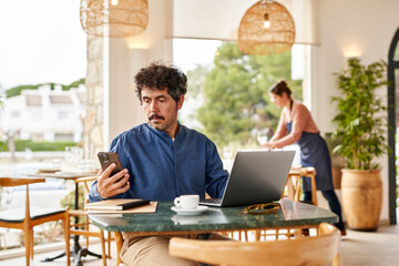 Male manager using devices in restaurant