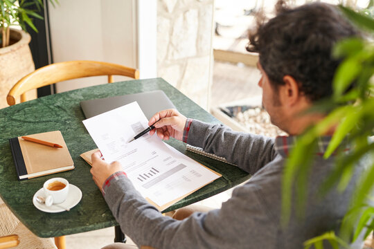 Smart businessman analyzing documents in cafe