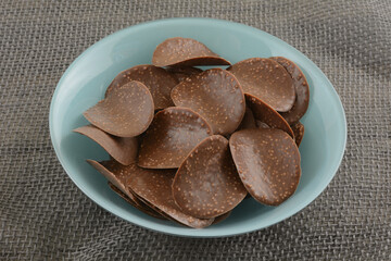 Chocolate covered chip crisps in blue snack bowl on gray burlap