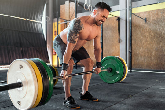 Muscular sportsman doing deadlift exercise in gym