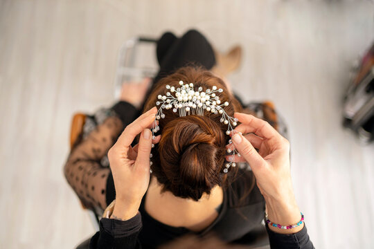 Unrecognizable hairdresser putting hair comb in hair of woman