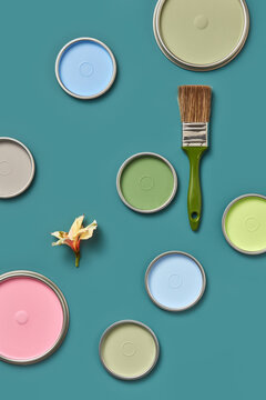 Colorful lids of paints with brush and spring flower