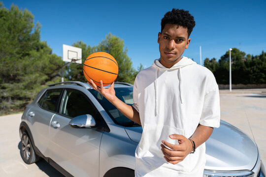 Basketball player leaning on car