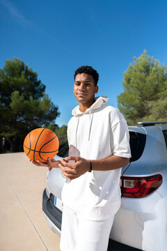 Basketball player leaning on car
