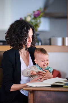 Mother with crying baby working at home