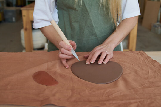 Woman sculpts from clay in workshop