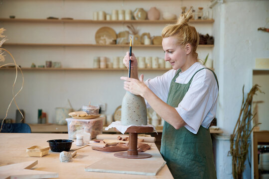 Smiling Woman Ceramist Aligns Her Vase