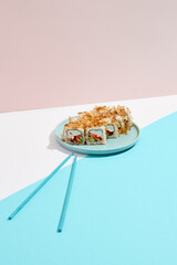 Maki roll with tuna shavings on modern coloured background. Sushi roll with salmon, cheese, cucumber inside, tuna shaving outside. Bonito maki sushi in minimal style. Japanese menu concept.