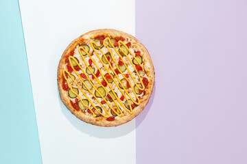Italian pizza with chicken and pickled cucumber on coloured background. Cheese pizza with chicken in minimal style on purple and blue colours. American pizza delivery concept with color backdrop