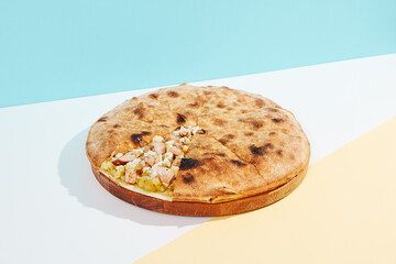Italian closed pizza with cheese, potatoes and chicken on coloured background. Chicken pie with cheese and potatoes in minimal style. American pizza delivery concept with color backdrop.