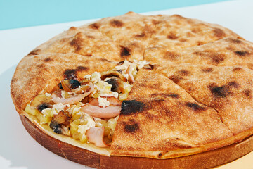 Italian closed pizza with mushroom, potatoes and chicken on coloured background. Mushroom pie with chicken and potatoes in minimal style. American pizza delivery concept with color backdrop.