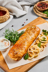 Meat pie with greens and onion on wood plate. Eastern food - beef pie with sesame. Eastern pastry with Minced meat.