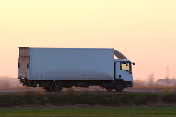 Cargo truck driving on highway hauling goods in evening. Delivery transportation and logistics...