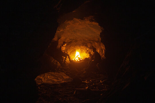 A couple enjoying a fire in a beach cave in the dark