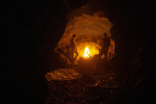A couple enjoying a fire in a beach cave at night