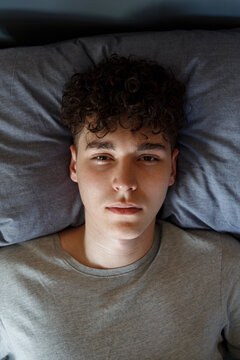 Tired guy lying on cozy bed and looking at camera