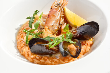 Italian dish - seafood risotto on white plate. Risotto frutti di mare with shrimp, mussels and squid. Seafood in marinara sauce with arborio rice. Paella with prawn and mussels. Seafood menu.