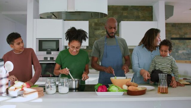 Happy multiracial family with three children cooking together at home.