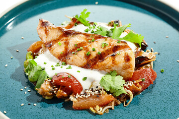 Healthy food - baked salmon steak with tomato salad and white sauce. Roast salmon with vegetables on contemporary plate in asian style. Restaurant dish - salmon filet with hard shadow.