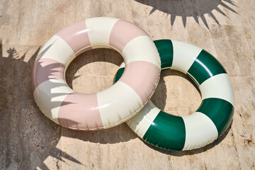 Multicolored swimming tubes on beige tiled poolside