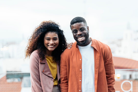 Cheerful black friends standing close on rooftop