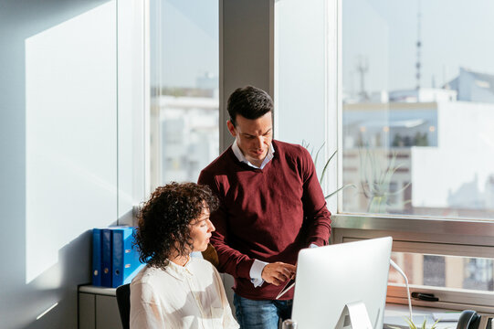 Happy colleague couple using computer in office desk