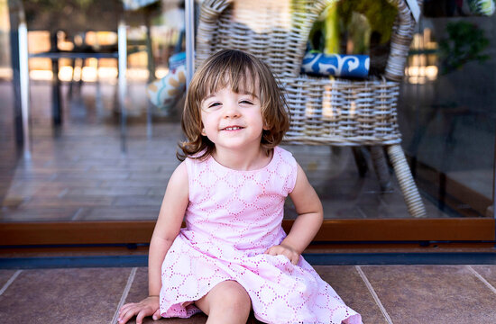 Happy little girl sitting on floor near window