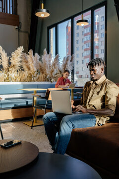 Multiracial people using laptops in modern space lit by sunlight