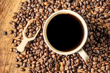 Black coffee in the cup, Dark Coffee beans on the old wooden floor,  Close up of seeds of coffee.