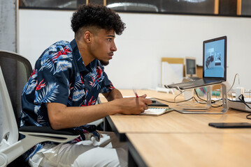 Black employee working on graphic tablet and laptop