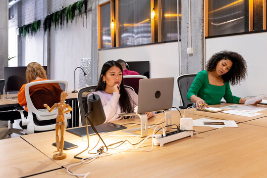 Multiracial colleagues working at desk in modern office