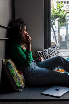 Black female freelancer speaking on cellphone near window